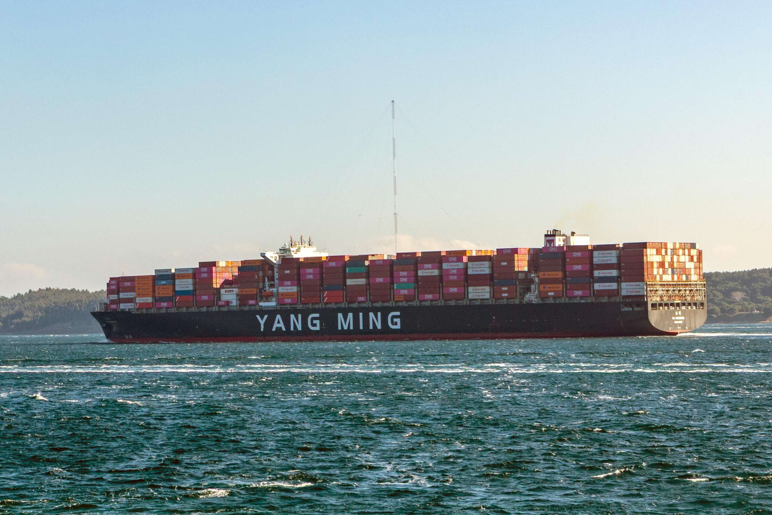 Yang Ming cargo ship loaded with containers sailing on a sunny day.